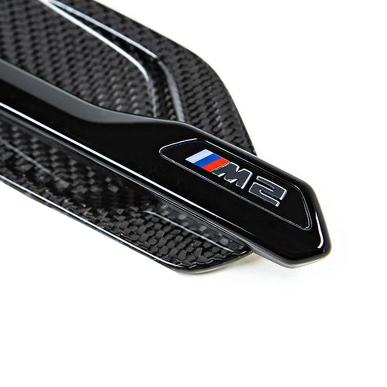 Close up of one gloss carbon and gloss black front wing badge for BMW M2 and M2 Competition vehicles.