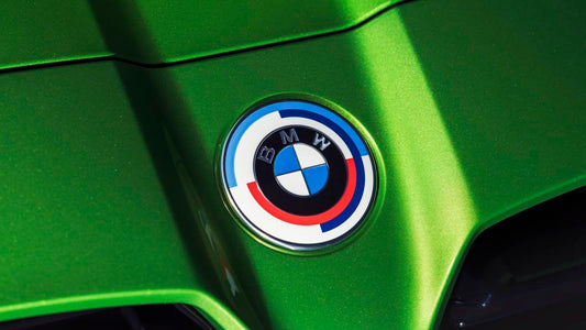 A Genuine BMW 50th Anniversary Heritage Badge Emblem on the front of a green BMW G82 M4.