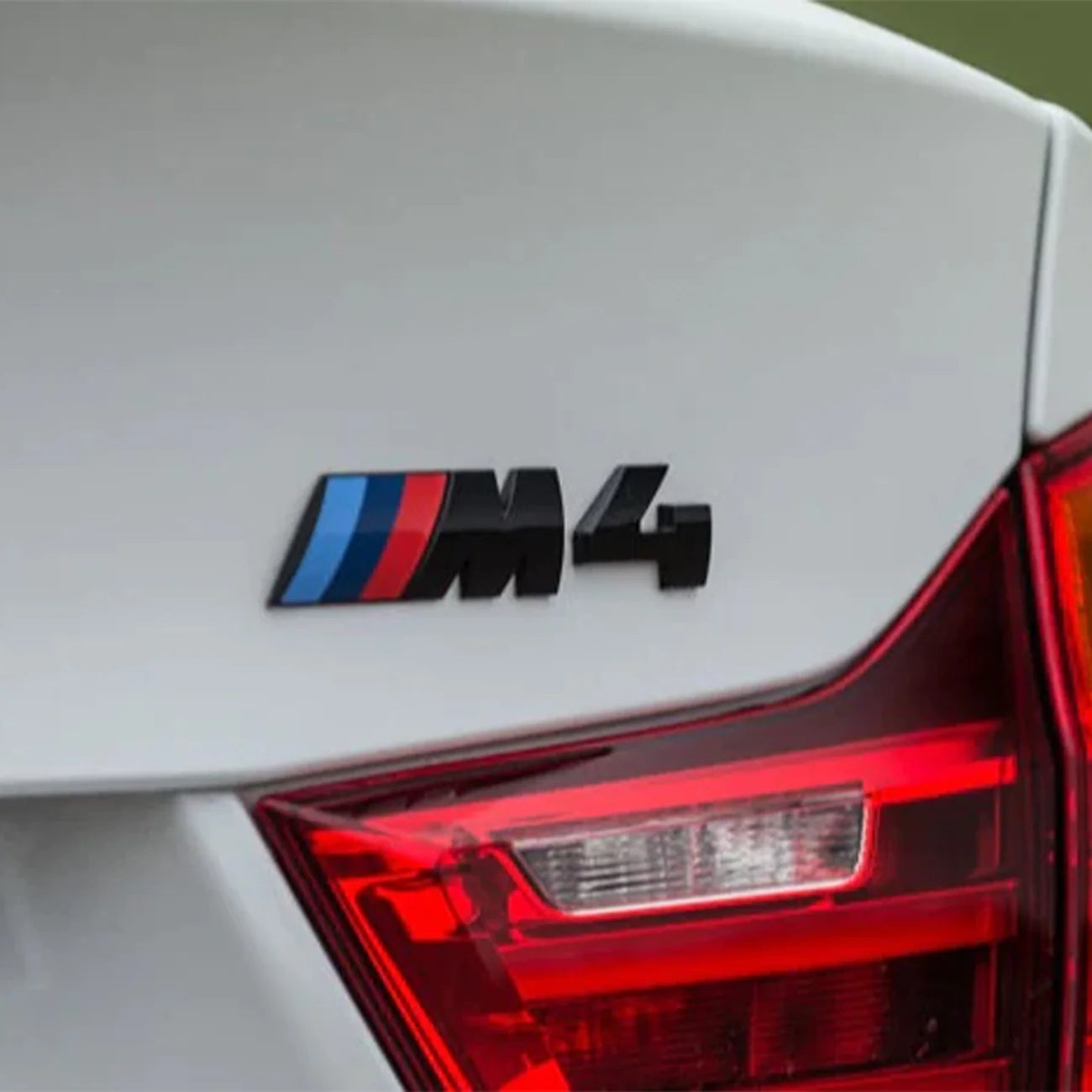 Gloss black BMW M4 replacement badge with M Colour accents on white BMW F82 M4