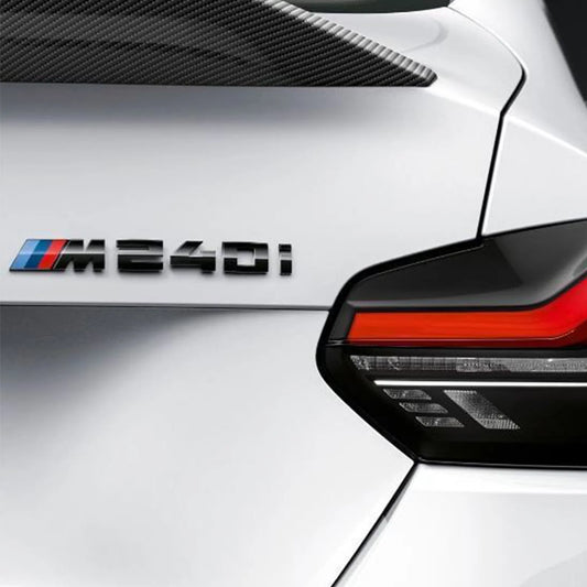 A genuine BMW M Performance gloss black rear model badge with the text 'M240I' on a white BMW M240i