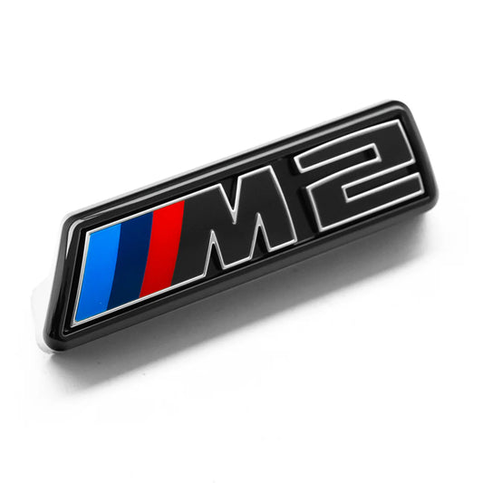 Gloss black front grille emblem with silver outline and the letters 'M2' for a BMW vehicle.
