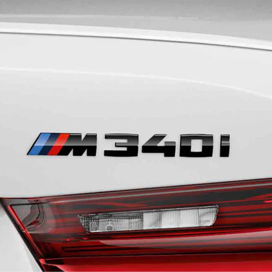 A gloss black BMW M340i OEM M Performance rear model badge with the BMW M logo in black, red, and blue colours on the back of a white BMW M340i